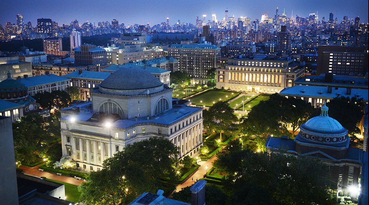 Columbia University's Morningside campus stands at dusk against the glowing New York City skyline, majestic