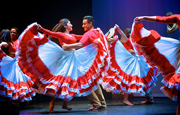 Woman in bright red and white dress twirls with a male partner