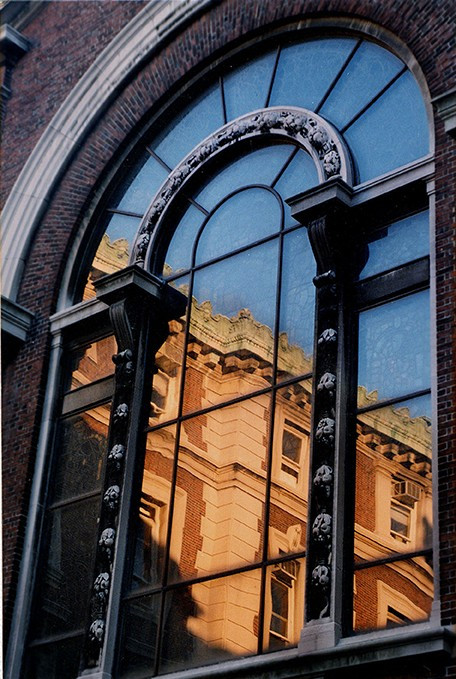 A window reflecting a view of a campus building.