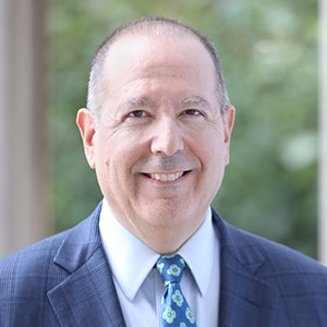 A man in a suit, smiling. 