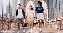 Three students walk across the brooklyn bridge