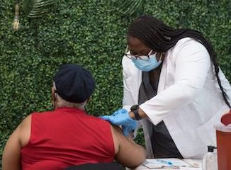 A health care worker administers a shot.